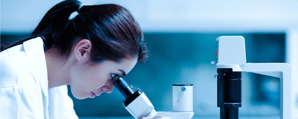 A woman is looking through a microscope in a laboratory.