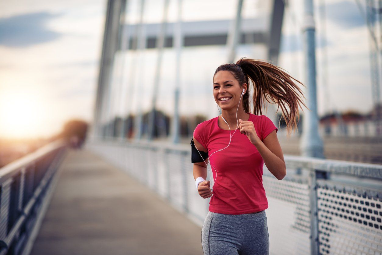 A woman is running on a bridge with headphones on.