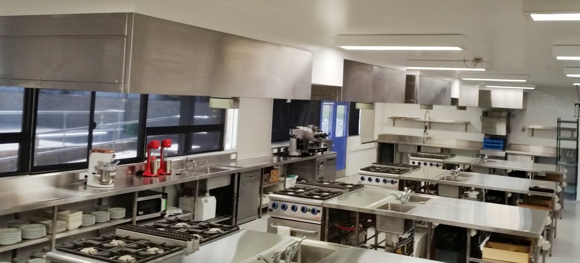 A large kitchen with lots of stainless steel appliances and tables.
