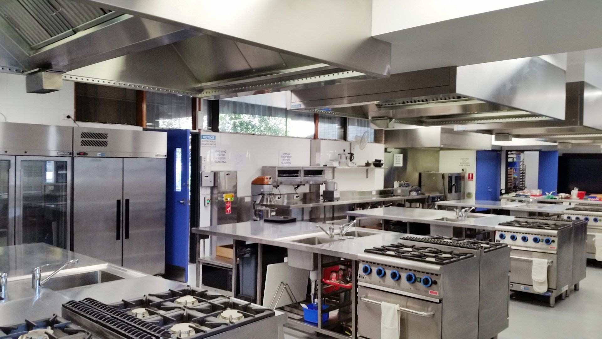 A large commercial kitchen with lots of stainless steel appliances.