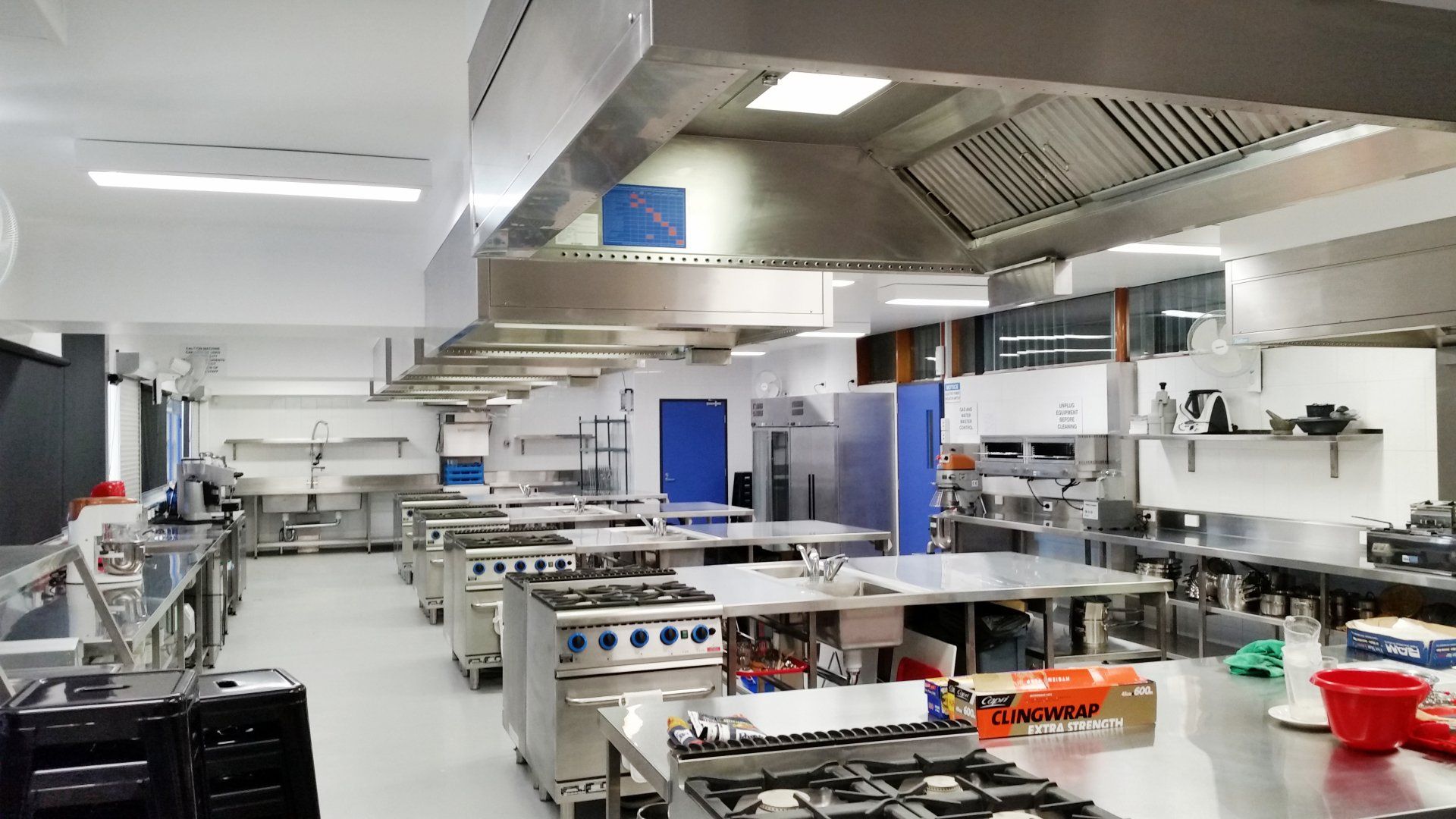 A large commercial kitchen with lots of stainless steel appliances.