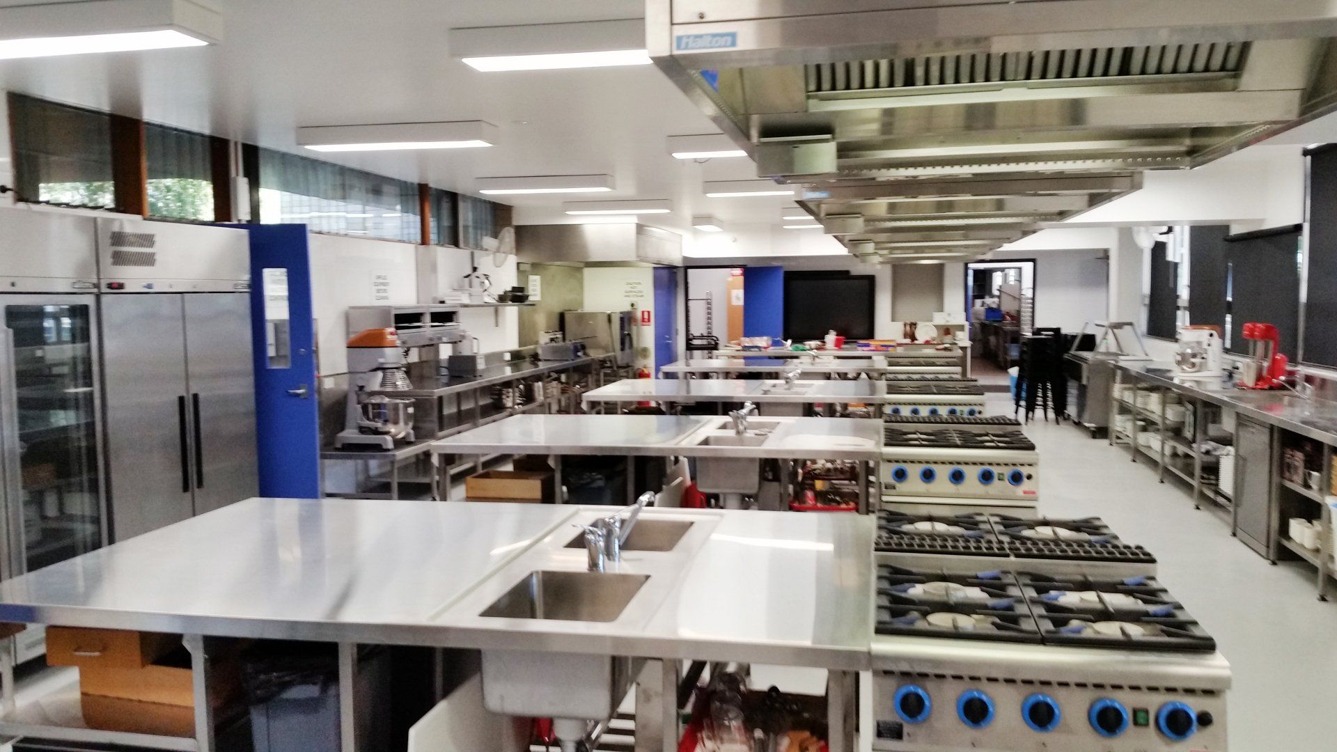 A large kitchen with lots of stainless steel appliances and tables.
