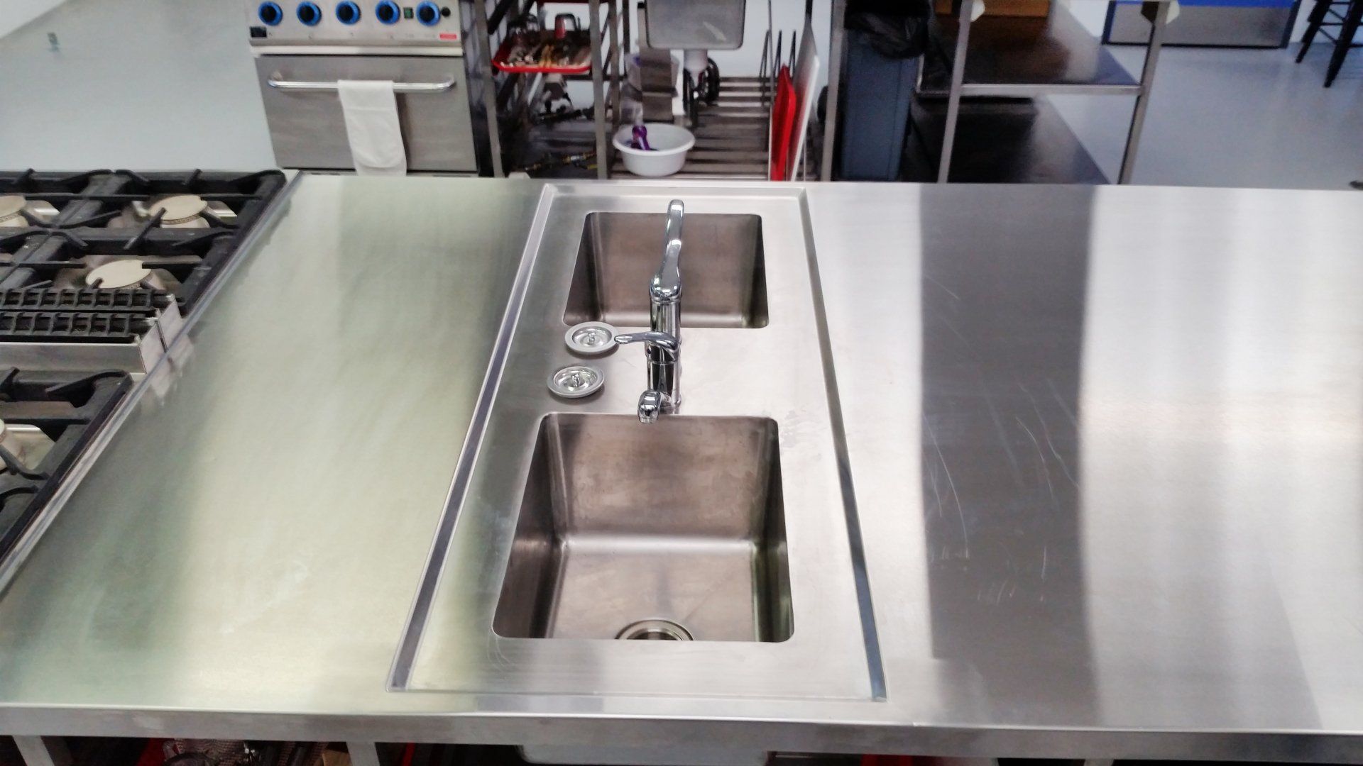 A stainless steel kitchen counter with two sinks and a stove.