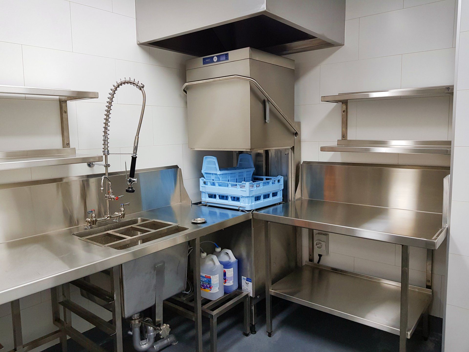A stainless steel kitchen with a sink and a dishwasher.