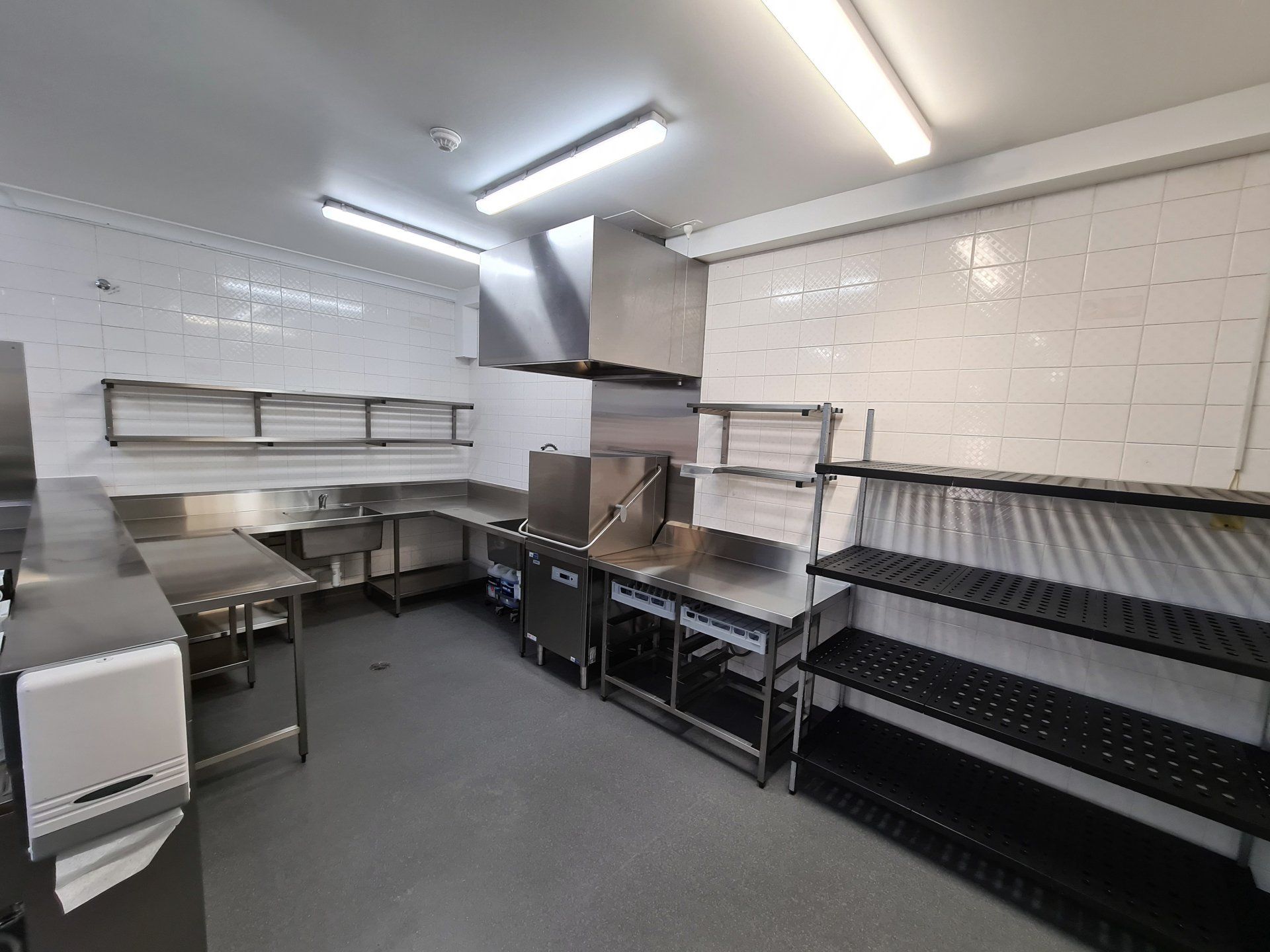 A kitchen with a lot of stainless steel appliances and shelves.