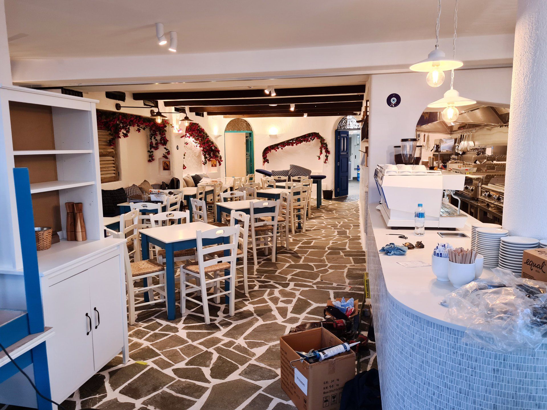 A restaurant with tables and chairs and boxes on the floor