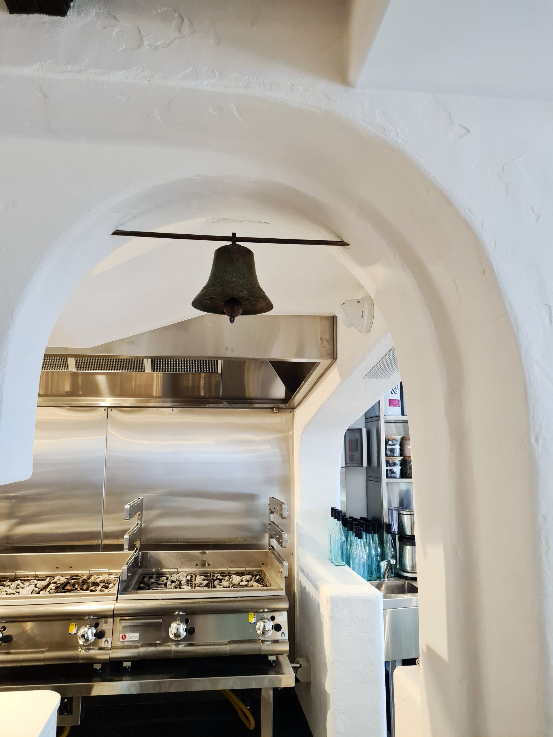A kitchen with a stove and a bell hanging from the ceiling.