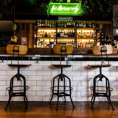 A row of bar stools are lined up in front of a bar with a sign that says ' exclusive bart '