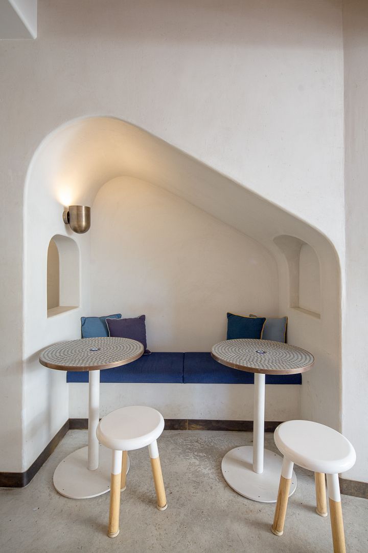 A corner of a room with two tables and two stools.