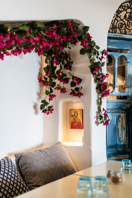 A room with a table and pillows and flowers on the wall