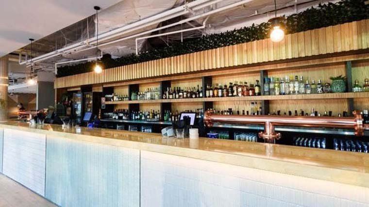 A long bar in a restaurant with a lot of bottles on the shelves.