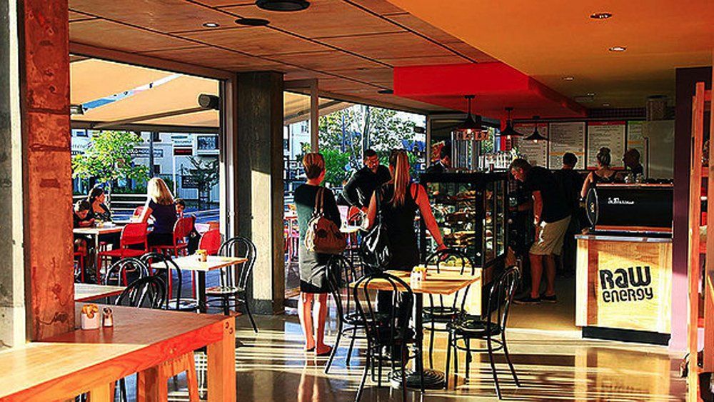 A group of people are sitting at tables in a restaurant called raw