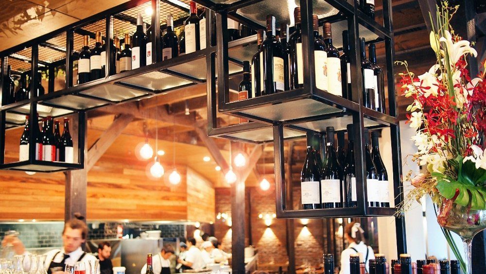 A restaurant with a lot of wine bottles hanging from the ceiling.