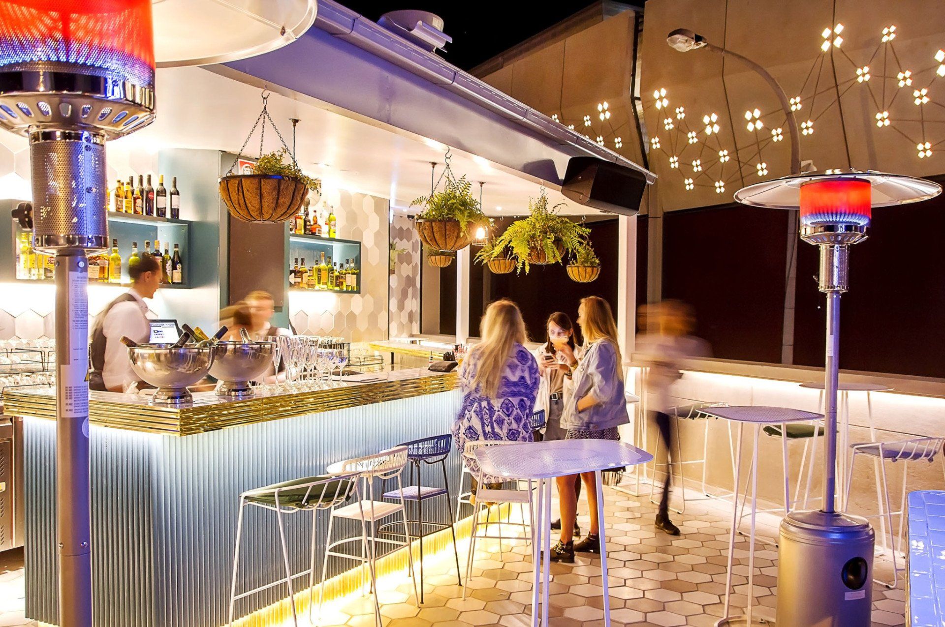 A group of people are sitting at tables in front of a bar.