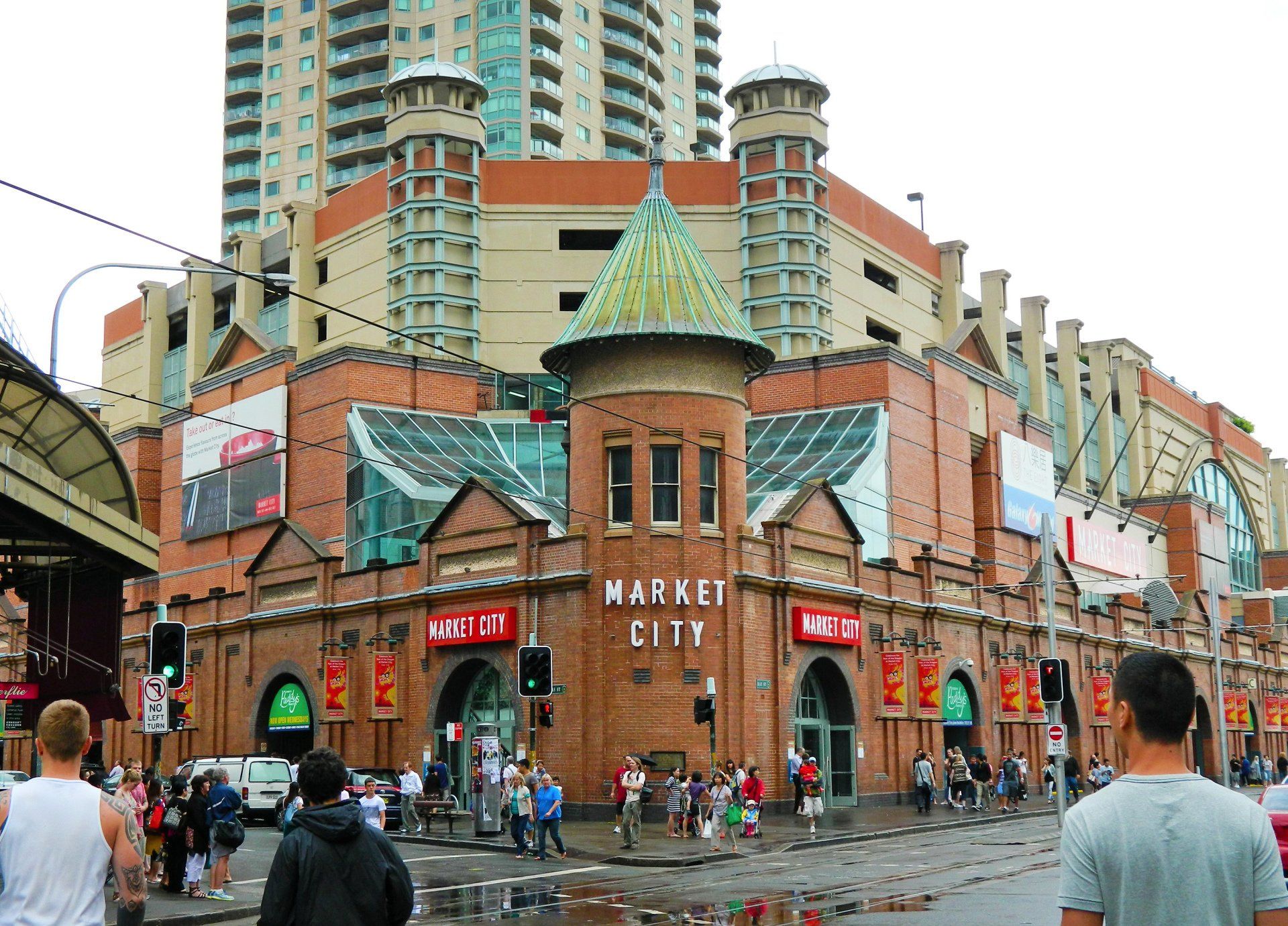 People are walking in front of a building that says market city