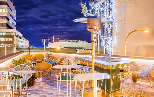 A rooftop restaurant with tables and chairs and a heater.