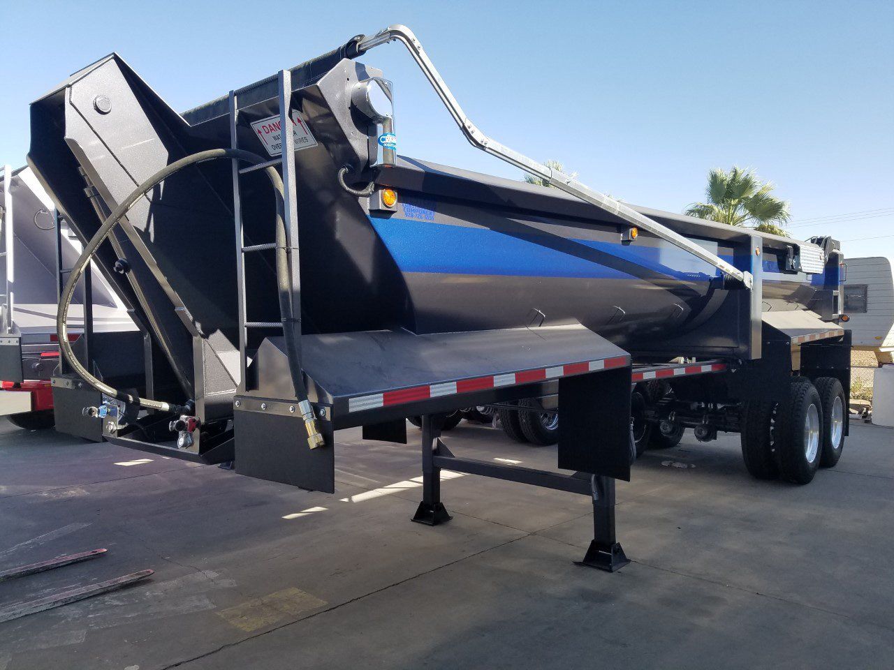 A blue and black dump truck is parked in a parking lot