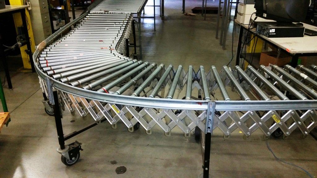 A conveyor belt is sitting on the floor in a warehouse.