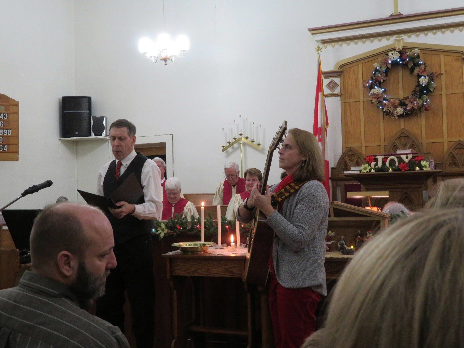 Two musicians performing at a church altar during a candlelit holiday service