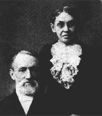 Black-and-white portrait of an older seated man and standing woman with a large lace collar.