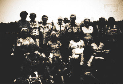 Group of people posing indoors in a dim, high-contrast black-and-white photo