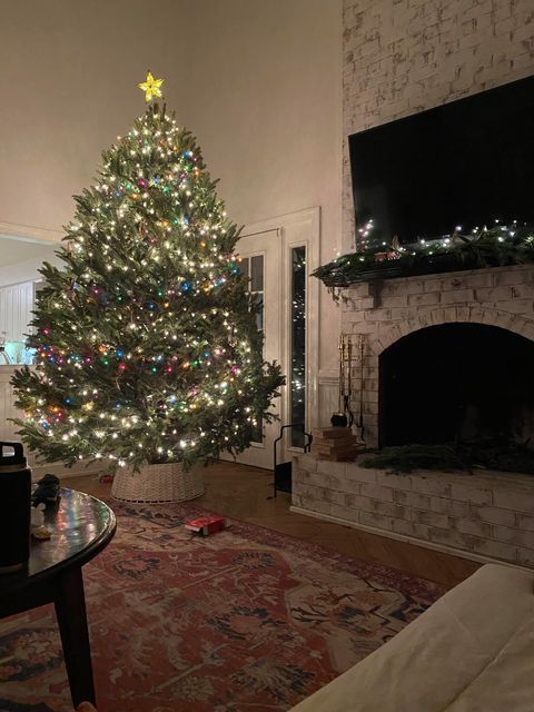 A living room with a christmas tree and a fireplace