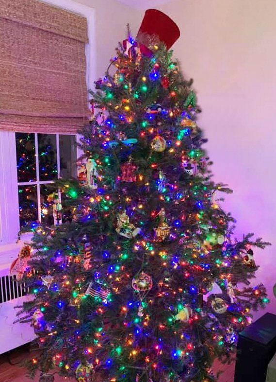 A christmas tree is sitting in a living room next to a window.