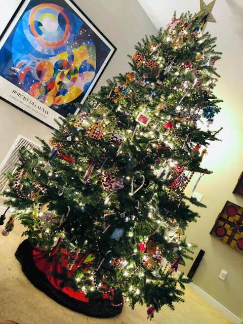 A christmas tree in a living room with a painting on the wall above it