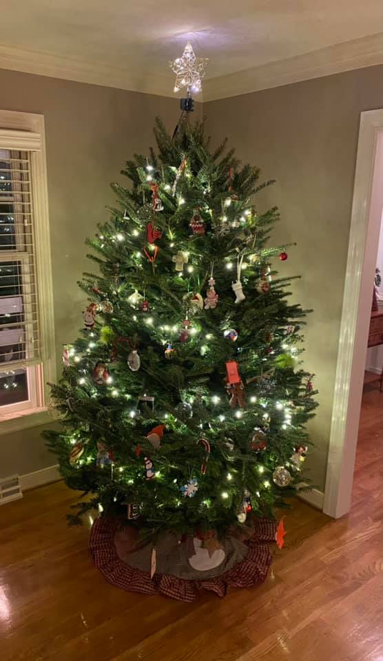 A christmas tree is sitting in a living room next to a window.