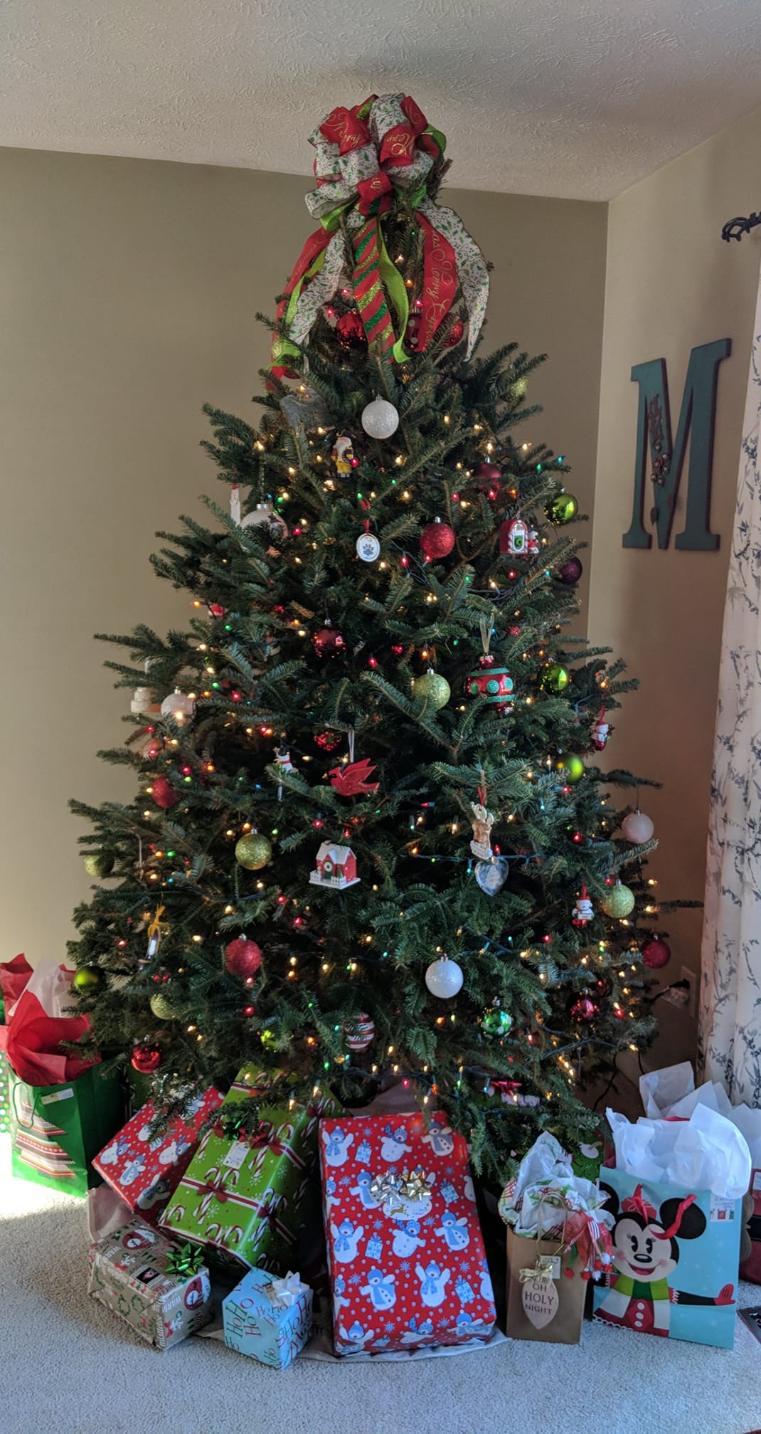 A christmas tree with lots of presents underneath it in a living room.