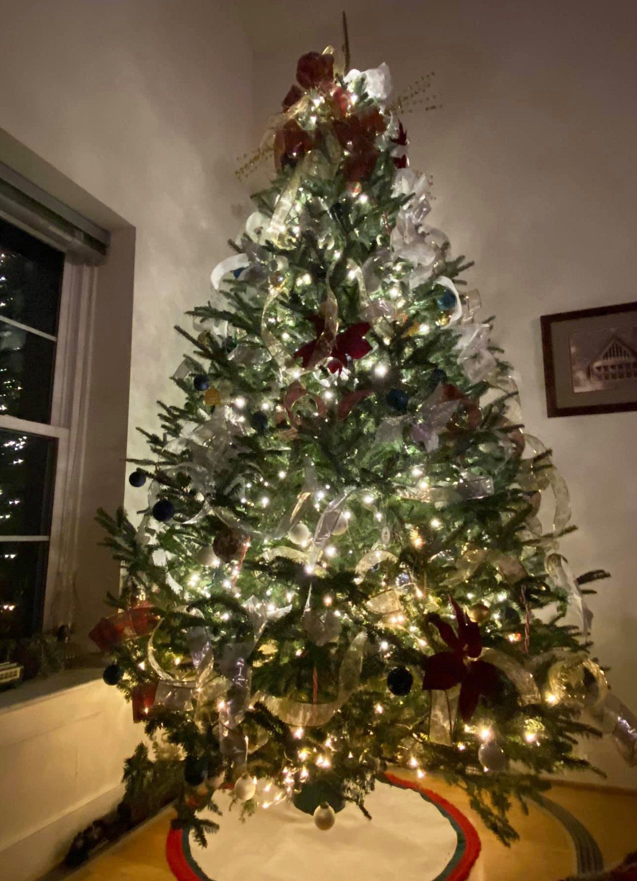 A christmas tree is sitting in a living room next to a window.