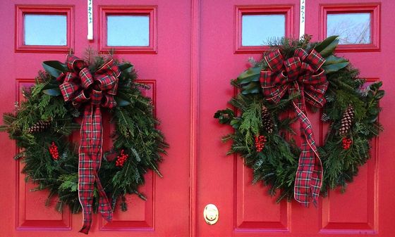 Two red doors with christmas wreaths on them
