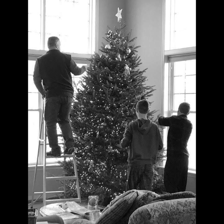 A black and white photo of a family decorating a christmas tree