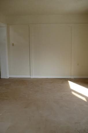 Empty room with beige carpet and off-white walls. Sunlight streams in from the right.