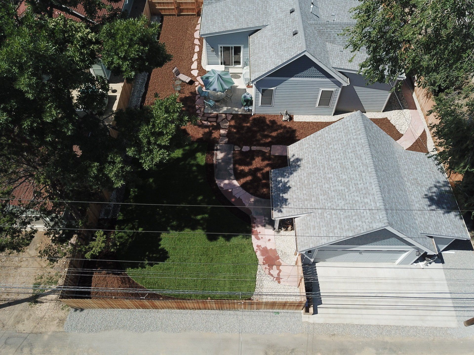 Aerial view of a gray house with a red brick path leading to a backyard.