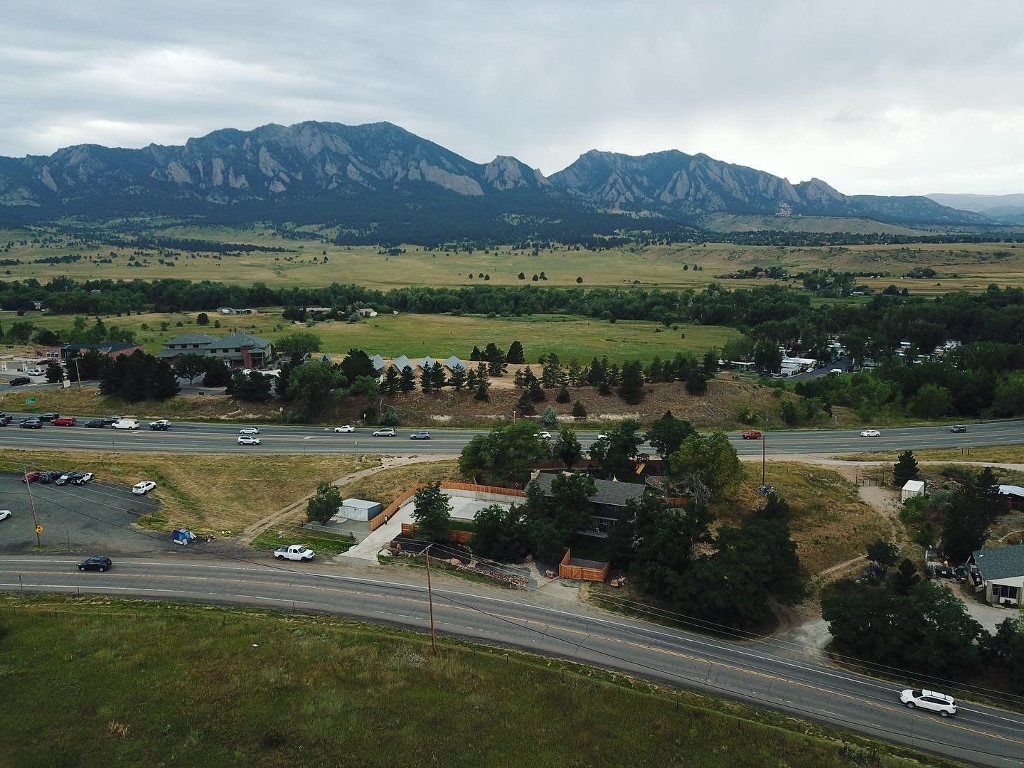 Mountain vista with highway, buildings, fields. Overcast sky.