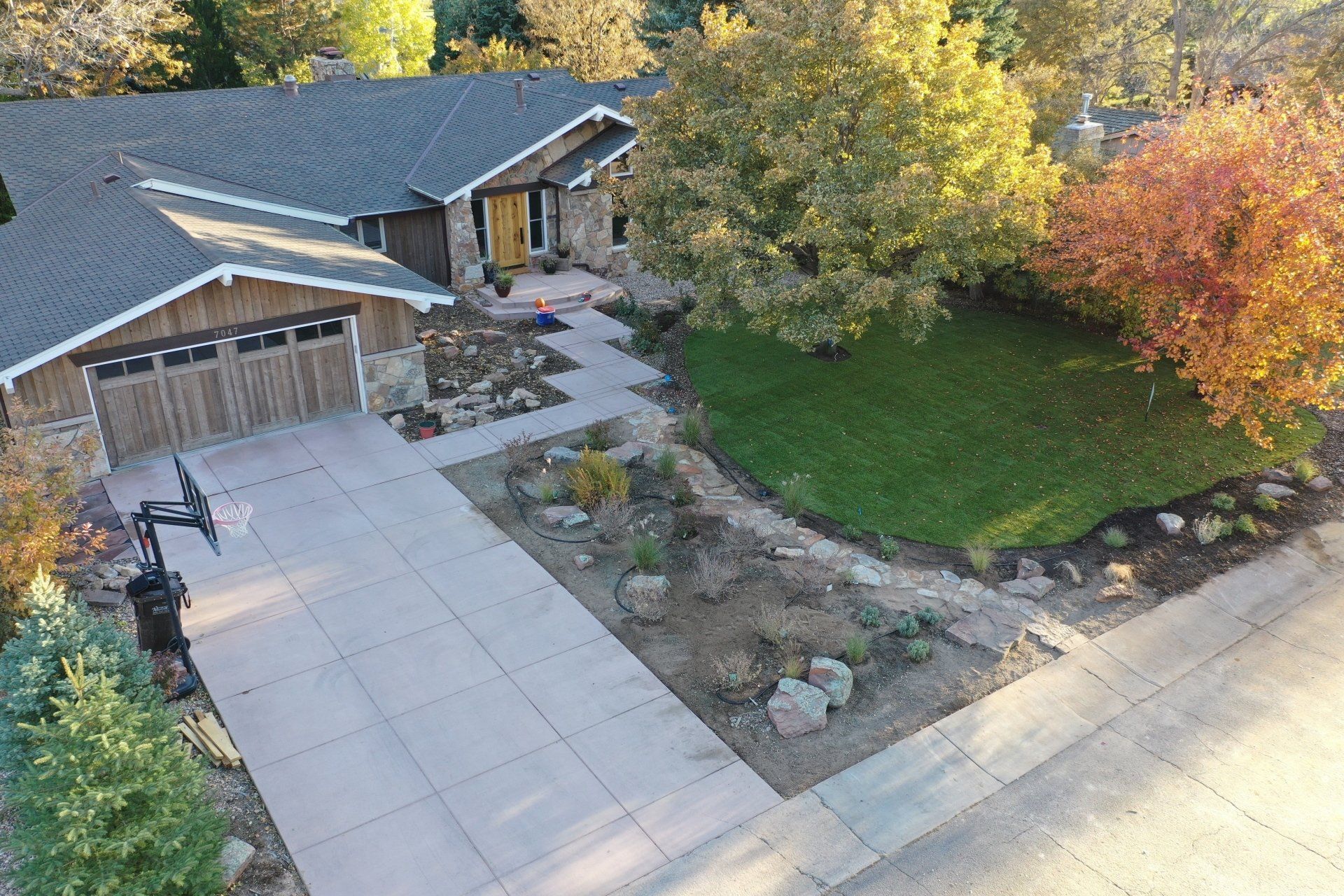 A house with a driveway, garage, and landscaping, with a basketball hoop on the side.