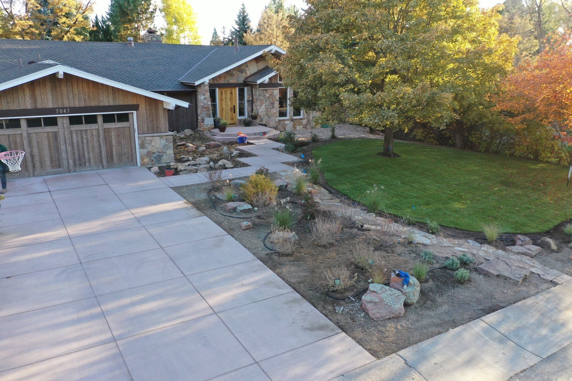 Exterior view of a house with a stone facade, driveway, and landscaping.