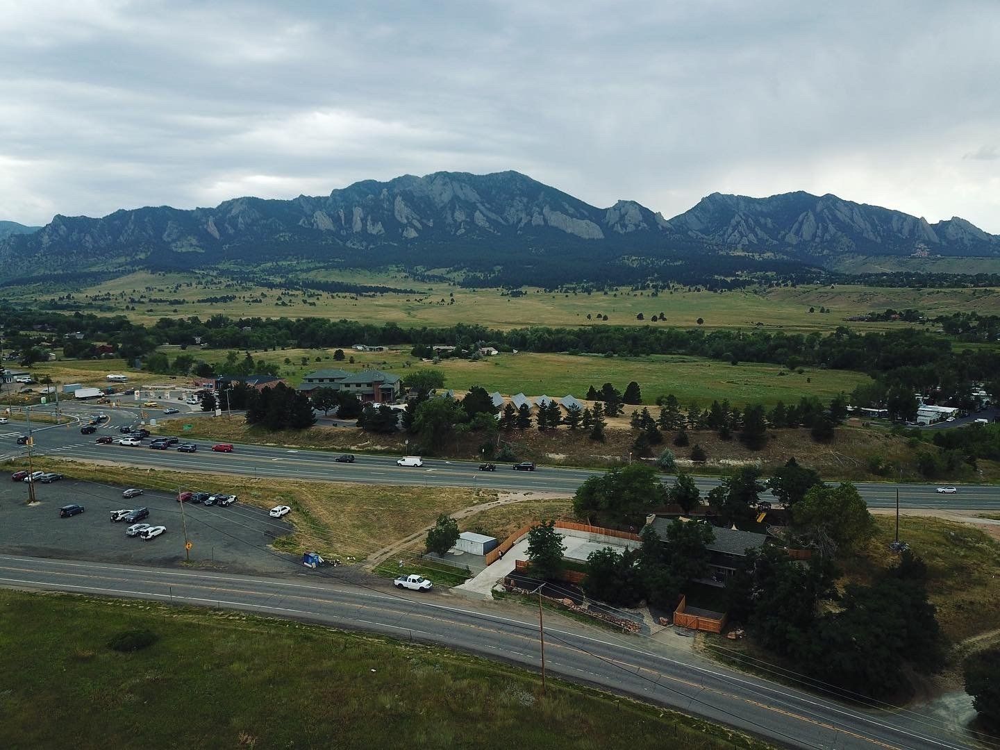 Green fields and buildings with mountains in the background under a cloudy sky.