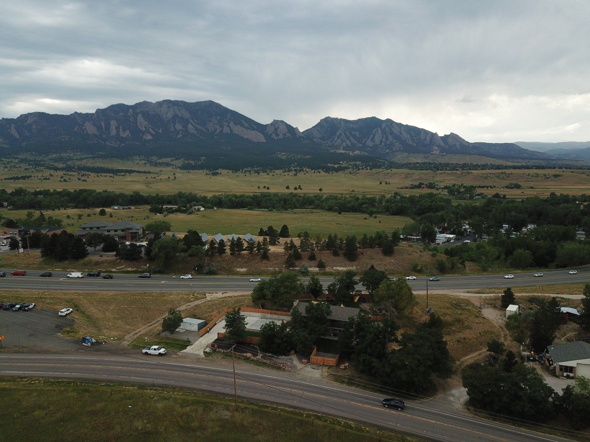 View of mountains, fields, and a road under a cloudy sky.
