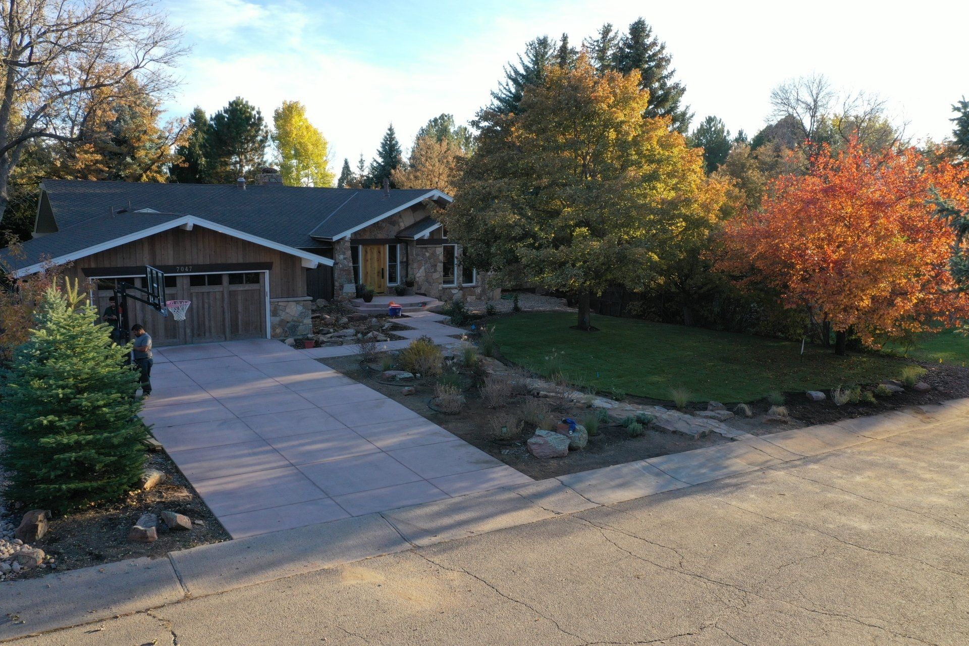 Ranch home with a stone facade, driveway, and autumn trees.