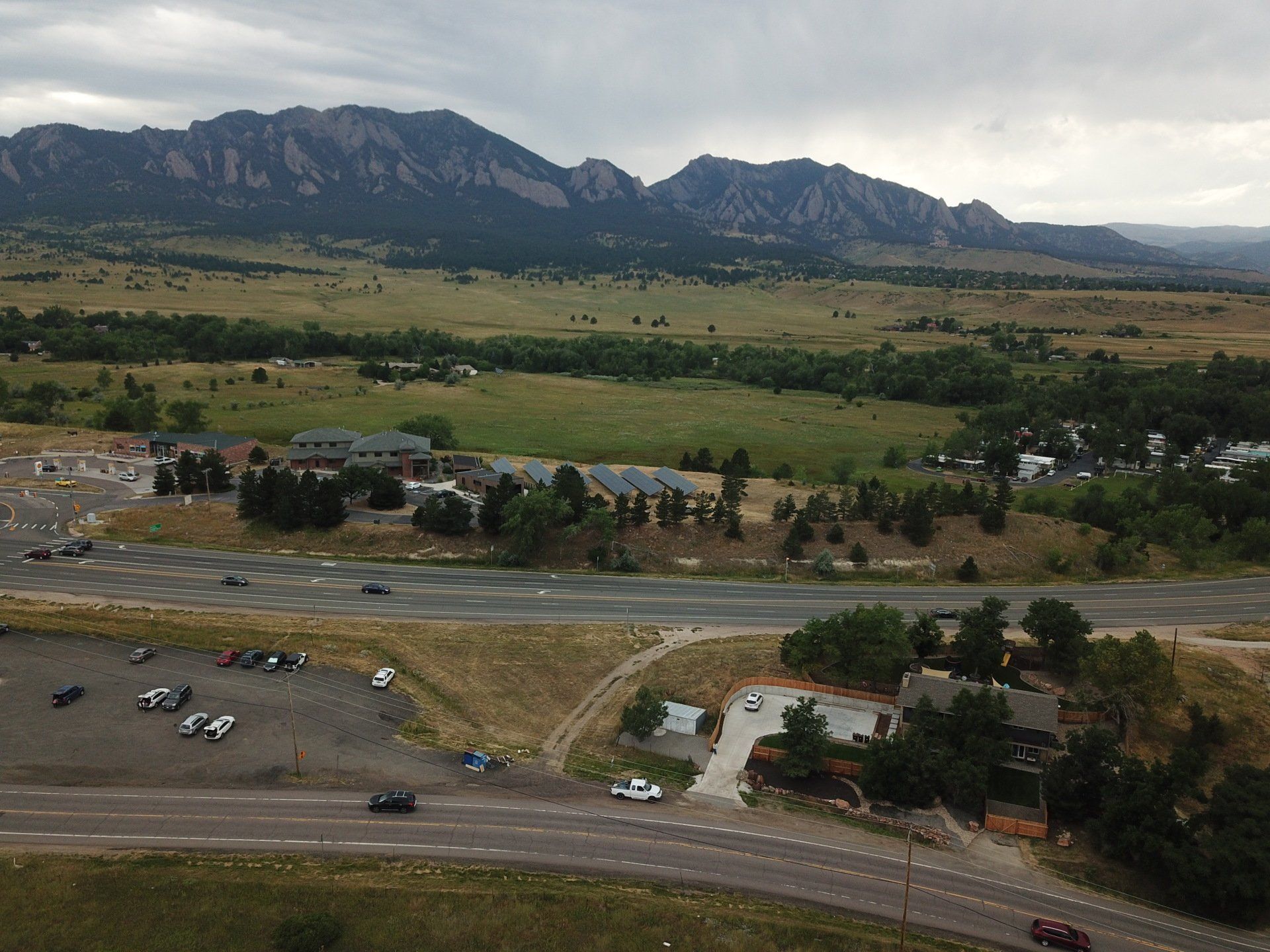 Mountain landscape with a building, parking area, road, and cloudy sky.