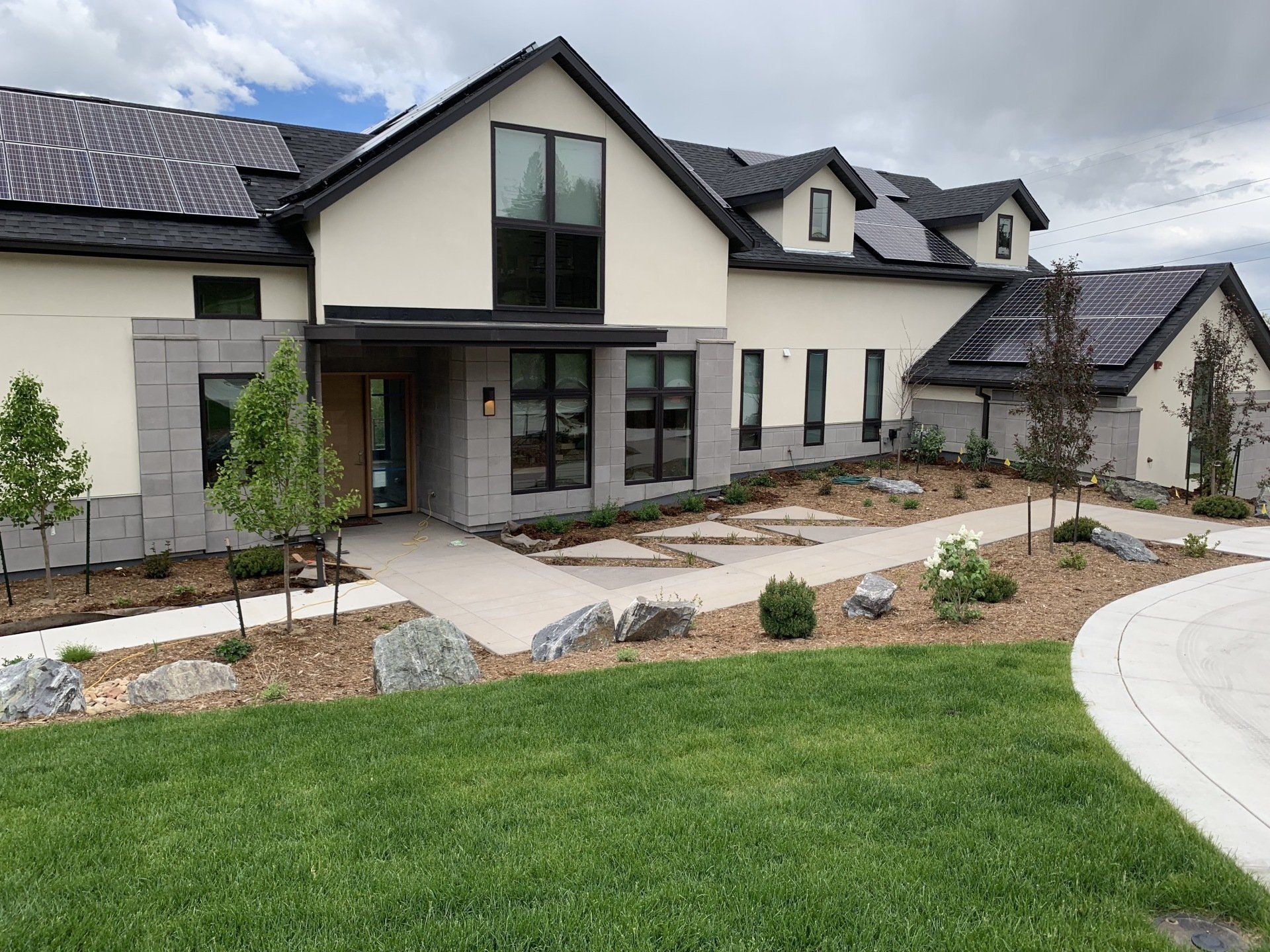 Modern house with solar panels on roof, light stucco walls, and stone accents.