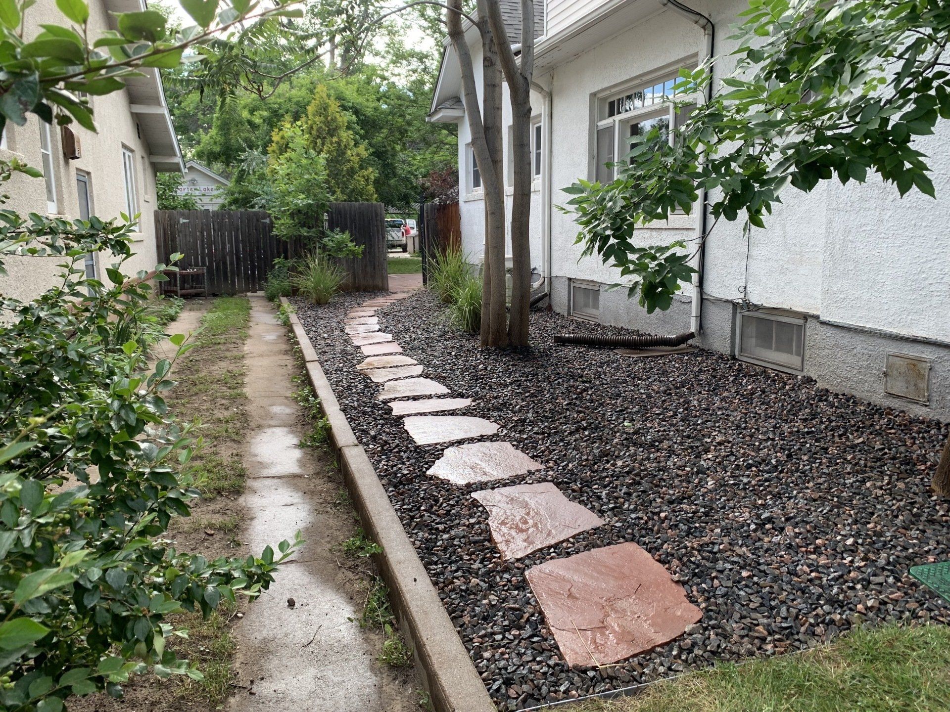 Stone path through a landscaped yard with black gravel and a white house.