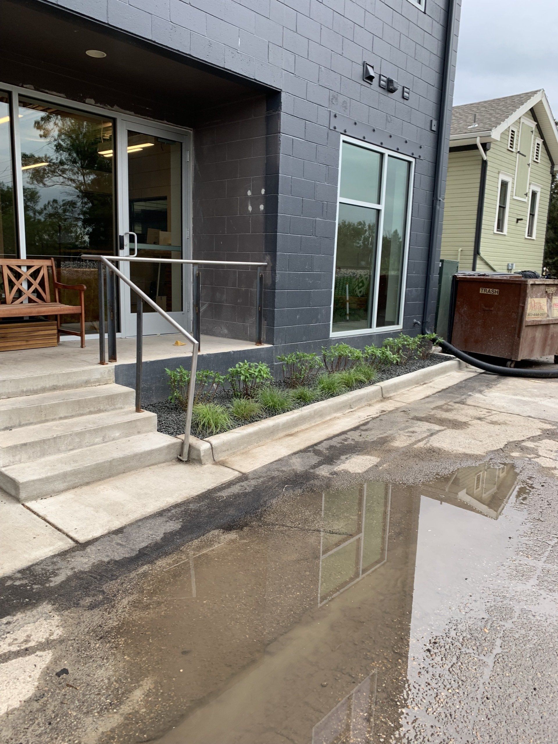 Exterior view of a modern building with a puddle in front of the entrance.