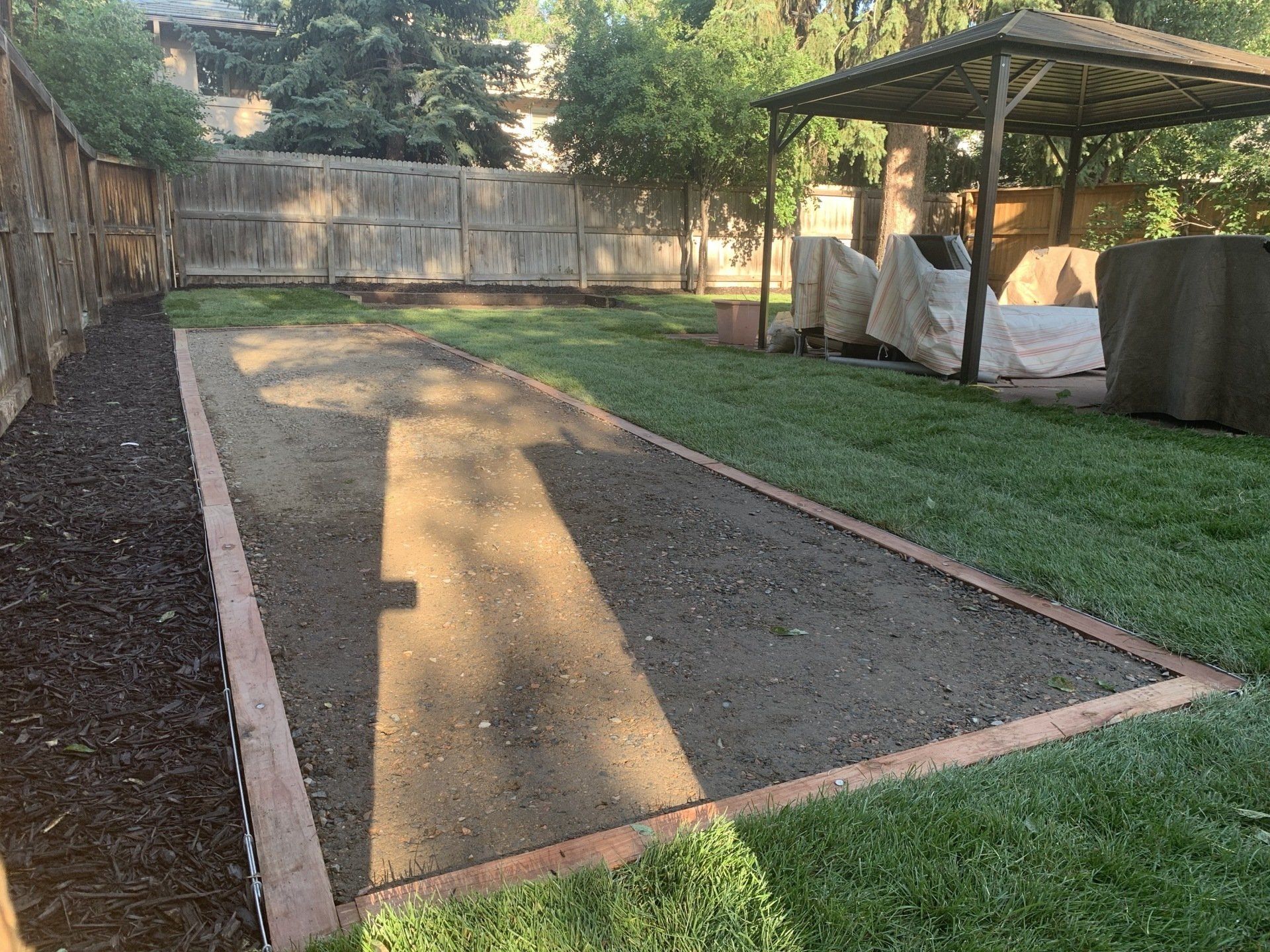 Backyard with a bocce ball court and a gazebo.