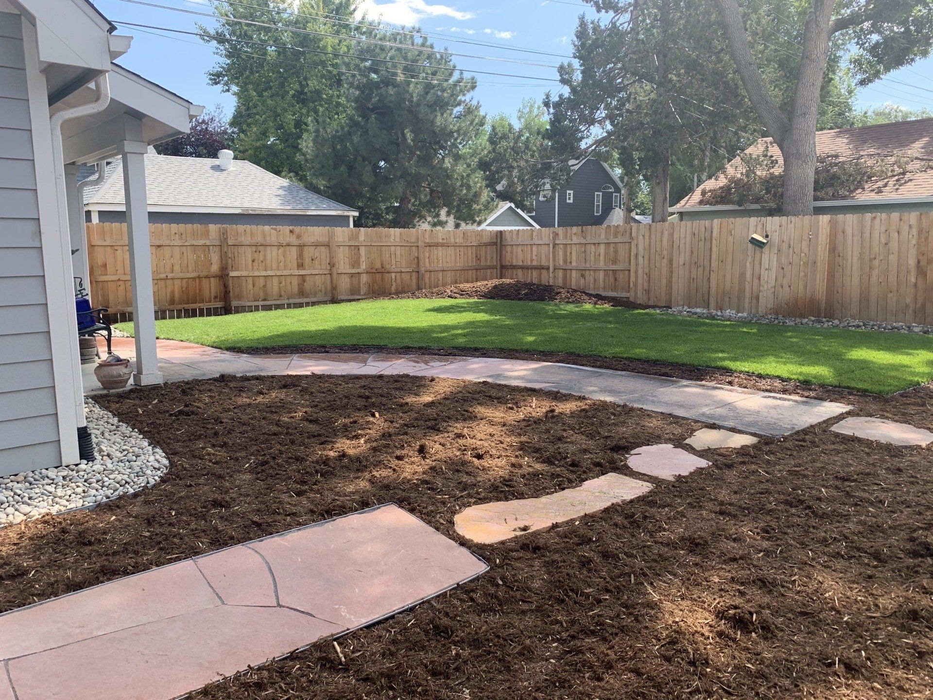 Backyard with a mulch pathway, grass, and a wooden fence.