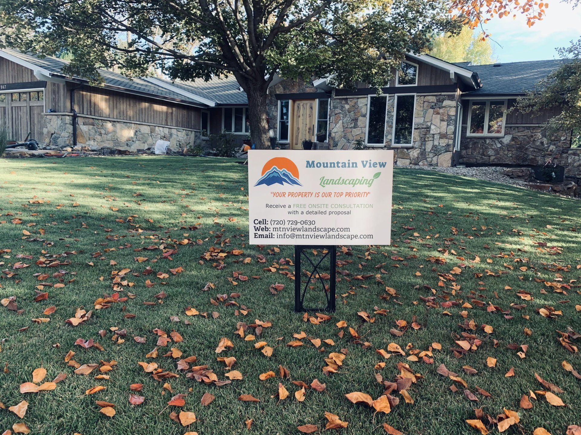 Sign for Mountain View Apartments in front of a stone building with a lawn covered in fallen leaves.