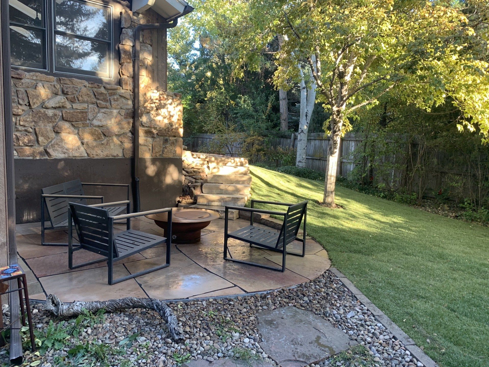 Patio with modern chairs, fire pit, and lawn in a backyard.