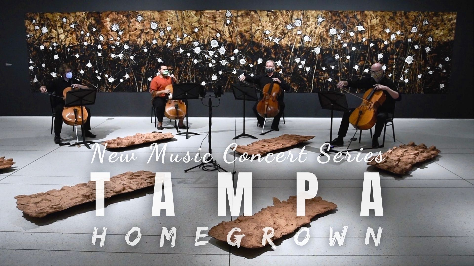 Cellists performing at a Tampa concert series with a backdrop of cotton fields and wood sculptures.